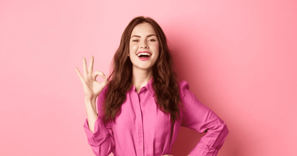 Happy customer wearing a pink dress putting up a an 'Okay' sign